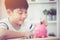 Asian Little boy saving money in pink piggy bank.