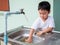 Asian little child boy helping to wash pot with happy face in relaxing family time.