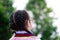 Asian little child girl with black hair braid turned her back to the camera. Children wear school uniforms and wear glasses.