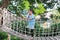 Asian little child girl playing on suspension wooden bridge. Kid walking on rope bridge Equipment at park playground