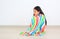 Asian little childd girl sitting wrapped covered in soft multicolor blanket and looking down in the room