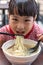 Asian little Chinese girl eating noodles soup