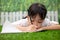 Asian Little Chinese girl kneeling on the grass and doing homework