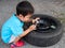 Asian little cute child boy playing repair car tire