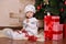 Asian little cute girl wearing casual dress posing close to new year christmas green classic tree with balls toys and colourful pr