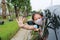 Asian little girl child wearing hygiene face mask pokes her head out of car window with show hand stop sign gesture during