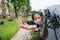 Asian little girl child wearing hygiene face mask pokes her head out of car window with show hand stop sign gesture