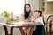 Asian little girl enjoy with bread eating and sit near her mother in the kitchen with fruit on the table. Main focus is little