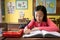 Asian little girl enjoy learning in classroom,portrait of a smiling child student studying holding pencil writing on book,sitting