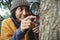 Asian little girl examining the tree stem through with magnifying glass While his mother stood behind in the morning