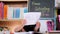 Asian little girl feeling sad and tired sitting at the table with many books and holding a paper with word Help. Learning difficul