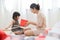 Asian Little girl and her Mother unwrapping a red gift box together.