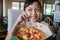 Asian little girl holding smartphone and ordering pizza to eat at home