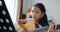 Asian little girl learning to play basic guitar by using acoustic guitar for beginner music instrumental self studying at home