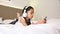 Asian little girl listening white head phone and mobile smartphone with happiness on the bed