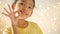 Asian little girl making okay hand gesture over glittering light background