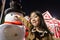 Asian little girl and snowman standing in the field,night view in the background of the house and christmas tree in a new yearâ€™s