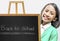 Asian little girl standing with a small chalkboard on a wooden easel