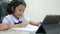Asian little girl in the Thai primary school uniform doing homework by using tablet smartphone for technology and education concep