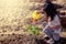 Asian little girl watering young tree with watering pot