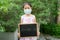 Asian little girl wearing a medicine face mask for virus protection and she standing hold the blackboard have `COVID-19` word.
