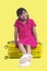 Asian little girl wearing pink mini dress in summer isolated on yellow background.
