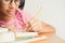 Asian little girl wears glasses while sit writing on  desk at her home