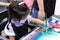 Asian little kid working on a painting on canvas during art class at school. Girl love to paint watercolor.