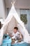 Asian little schoolboy using tablet pc computer learning at home in kids tent or teepee at home