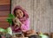 Asian little young girl look forward and smile among various types of vegetable also hold the radish behind hen on the table in