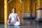 Asian long hair man relaxes meditation with all white costume sit in front of Buddist`s gold wallpaper in the Temple, Thailand