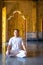 Asian long hair man relaxes meditation with all white costume sit in front of Buddist`s gold wallpaper in the Temple, Thailand