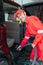 Asian male car cleaner wears red smiling uniform while cleaning car floor