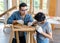 Asian male carpenter woodworker engineer dad in jeans outfit with safety gloves and glasses goggles helping teaching son using