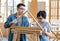 Asian male carpenter woodworker engineer dad in jeans outfit with safety gloves and glasses goggles helping teaching son using