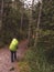 An Asian male carrying a large backpack with fluorescent greens walks in the forest trail