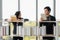 Asian male and cuacasian female university students standing at bookshelf seaching and reading book in library