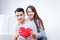 Asian male and female couples hold a red heart shaped pillow