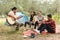 Asian male and female tourists are tenting and partying, chatting, singing and playing guitar in the forest