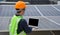 An Asian male inspector checks the circuit system with a laptop during maintenance of a kit at a rooftop solar power plant of a