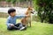 Asian male kid sitting and playing together with Shiba inu dog in public park