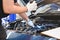 Asian male mechanic hold and shining flashlight to examine car engine problem in front of automotive vehicle car hood. Safety