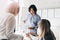 Asian male office worker with wristwatch holding documents with diagrams while talking with female colleagues. Indoor