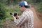 Asian male photographer or videographer holding camera and shooting natural wildlife, safari trip in the wild, nature journey