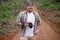 Asian male photographer or videographer holding camera and shooting natural wildlife, safari trip in the wild, nature journey