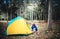 Asian male tourist, Pitch a yellow tent for Camping in a forest with tall trees