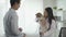 Asian male veterinarian wearing protective mask and female assistant examining dog