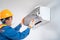 Asian male wear a safety mask to prevent dust technician is pulling a dusty filter from the air conditioner to cleaning air