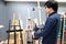 Asian man artist choosing art frame stand in stationery shop