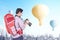 Asian man with backpack and camera looking at colorful air balloon flying